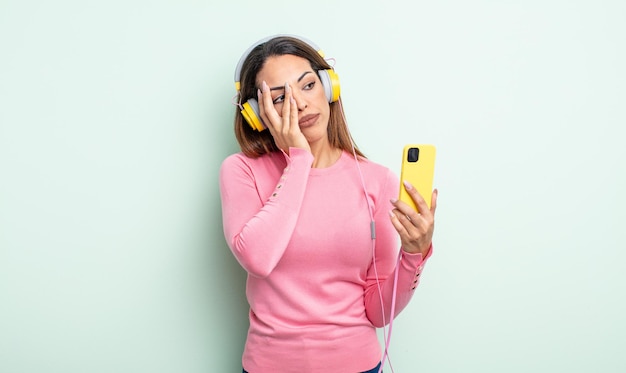 Pretty hispanic woman feeling bored, frustrated and sleepy after a tiresome. smartphone and headphones concept