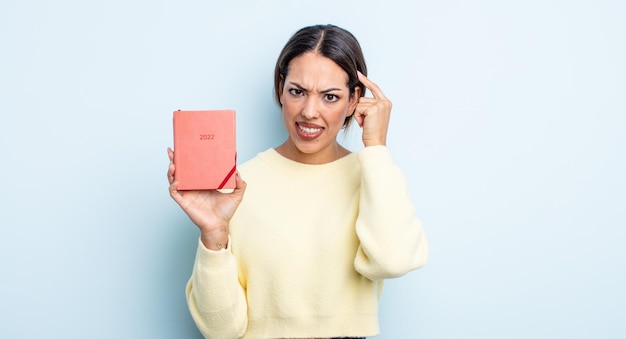 Pretty hispanic woman feeling confused and puzzled, showing you are insane. agenda concept