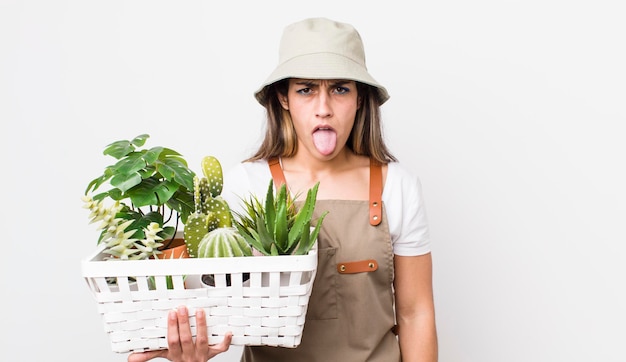 Pretty hispanic woman feeling disgusted and irritated and tongue out plants and gardering concept