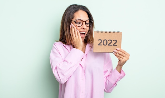 Pretty hispanic woman feeling happy, excited and surprised. 2022 calendar concept