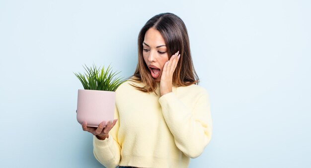 幸せ、興奮、驚きを感じているかなりヒスパニック系の女性。観葉植物のコンセプト