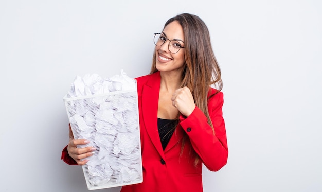 Pretty hispanic woman feeling happy and facing a challenge or\
celebrating. paper balls failure concept