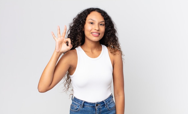 Pretty hispanic woman feeling happy, relaxed and satisfied, showing approval with okay gesture, smiling