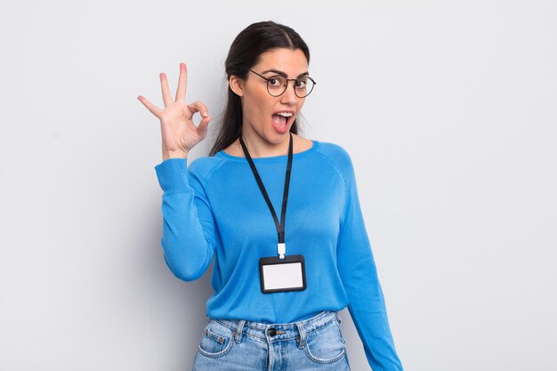 Pretty hispanic woman feeling happy, showing approval with okay gesture. accreditation concept