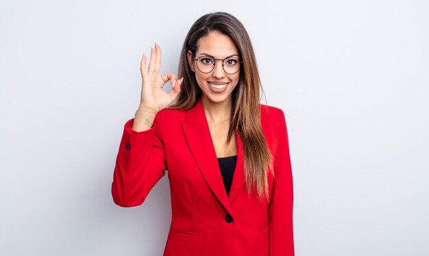 Pretty hispanic woman feeling happy showing approval with okay gesture businesswoman concept