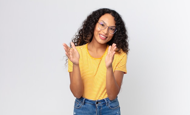 Pretty hispanic woman feeling happy and successful, smiling and clapping hands, saying congratulations with an applause