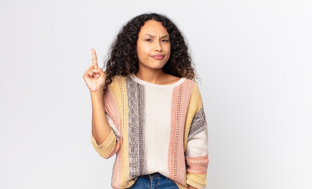 Pretty hispanic woman feeling like a genius holding finger proudly up in the air after realizing a great idea, saying eureka