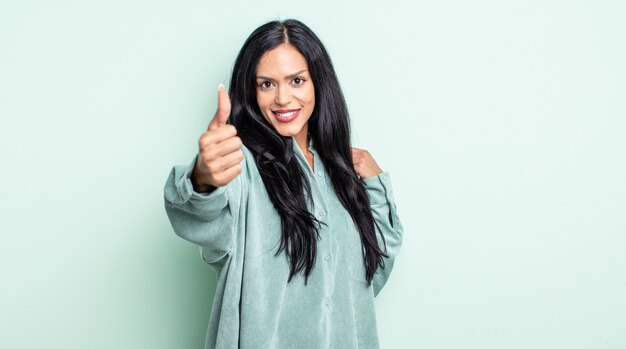 Pretty hispanic woman feeling proud, carefree, confident and happy, smiling positively with thumbs up