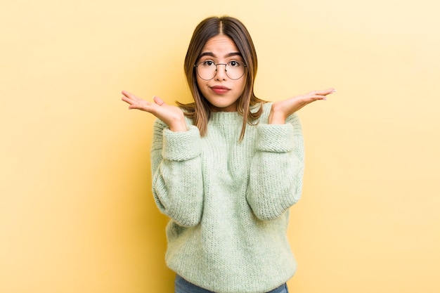 Pretty hispanic woman feeling puzzled and confused doubting weighting or choosing different options with funny expression