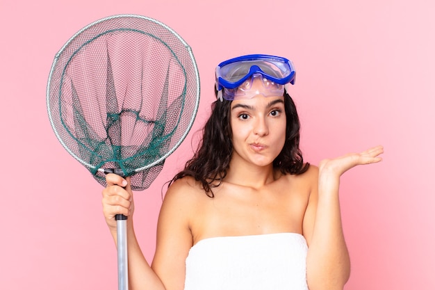 Pretty hispanic woman feeling puzzled and confused and doubting with goggles and fishing net