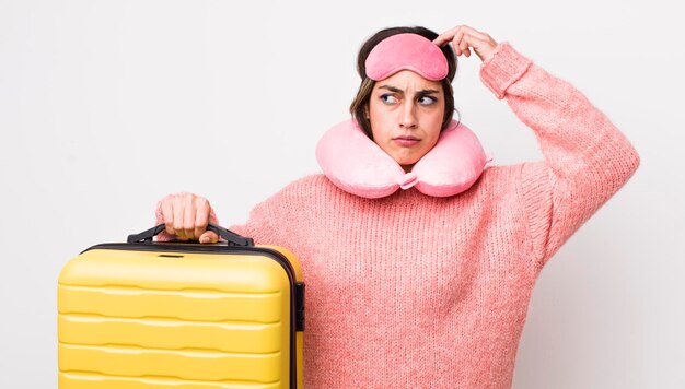 Pretty hispanic woman feeling puzzled and confused scratching head flight passenger concept