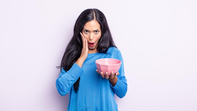 Pretty hispanic woman feeling shocked and scared. empty bowl concept