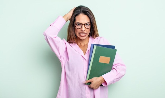 Pretty hispanic woman feeling stressed, anxious or scared, with hands on head. notebooks concept