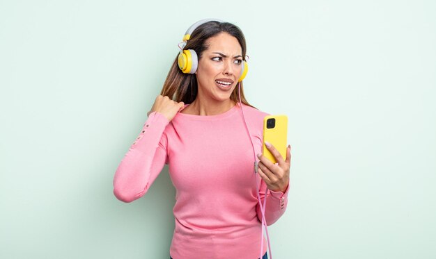 Pretty hispanic woman feeling stressed, anxious, tired and frustrated. smartphone and headphones concept