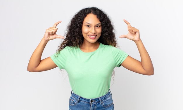 Pretty hispanic woman framing or outlining own smile with both hands, looking positive and happy, wellness concept