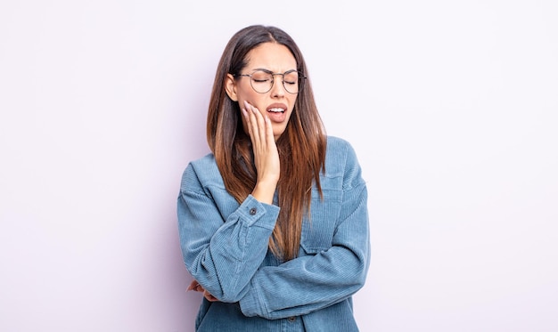 Pretty hispanic woman holding cheek and suffering painful toothache, feeling ill, miserable and unhappy, looking for a dentist