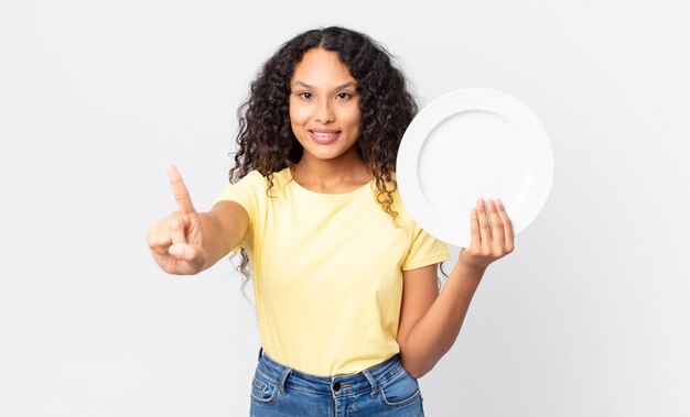 Pretty hispanic woman holding an empty clean dish