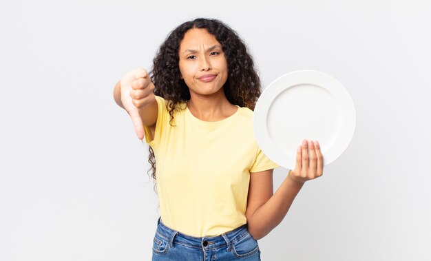 Pretty hispanic woman holding an empty clean dish