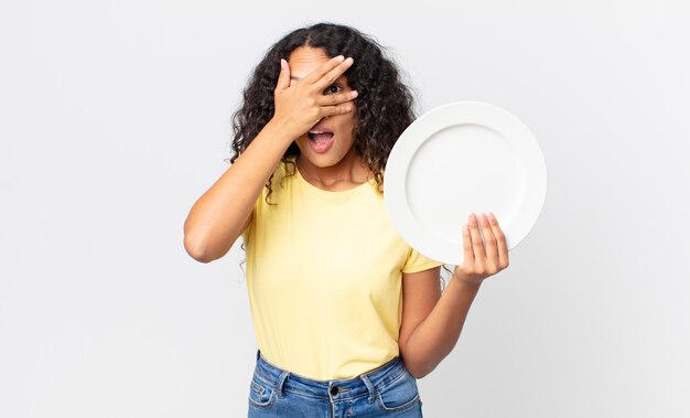 Pretty hispanic woman holding an empty clean dish