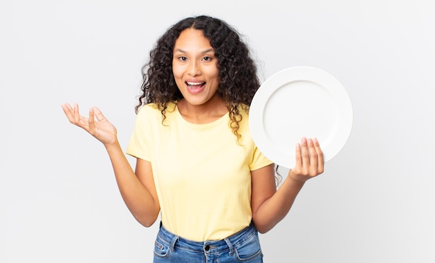 Pretty hispanic woman holding an empty clean dish