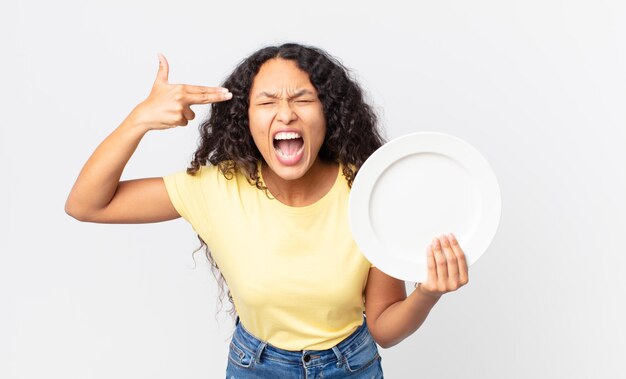 Pretty hispanic woman holding an empty clean dish