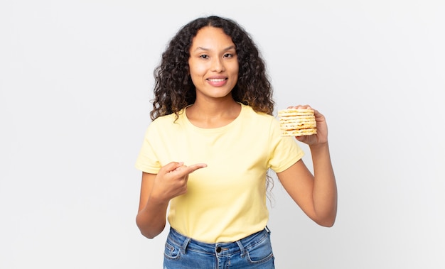 Pretty hispanic woman holding a rice diet cakes