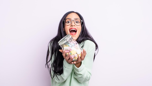 Pretty hispanic woman looking desperate, frustrated and stressed jelly candies concept