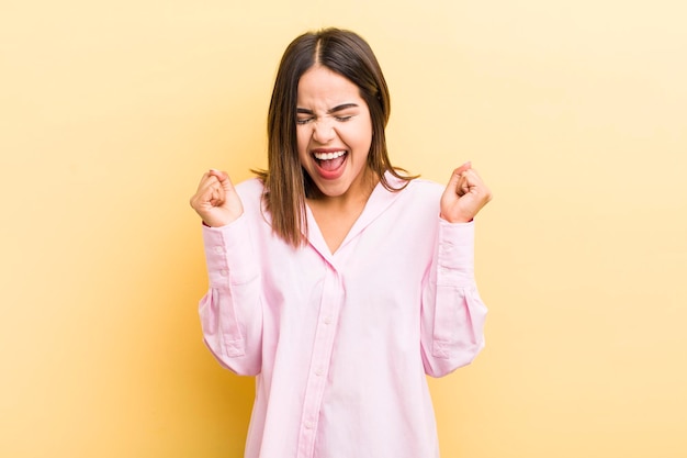Pretty hispanic woman looking extremely happy and surprised celebrating success shouting and jumping