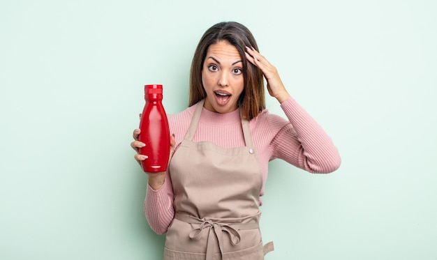 Pretty hispanic woman looking happy, astonished and surprised. ketchup concept