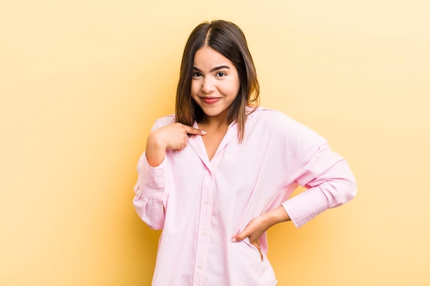 Pretty hispanic woman looking happy proud and surprised cheerfully pointing to self feeling confident and lofty