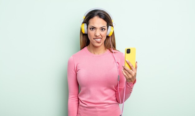 Pretty hispanic woman looking puzzled and confused. smartphone and headphones concept