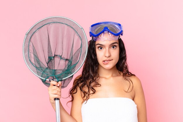 Pretty hispanic woman looking puzzled and confused with goggles and fishing net