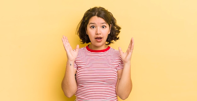 Pretty hispanic woman looking shocked and astonished with jaw dropped in surprise when realizing something unbelievable