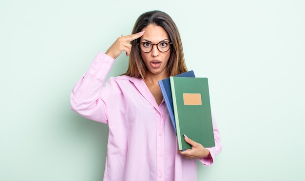 Pretty hispanic woman looking surprised, realizing a new thought, idea or concept. notebooks concept