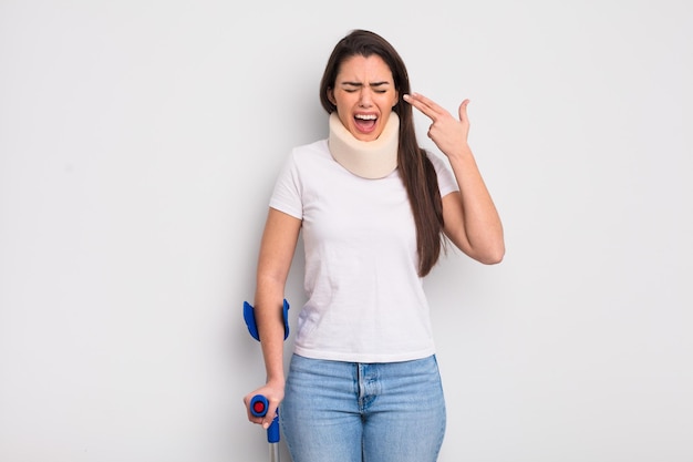 Pretty hispanic woman looking unhappy and stressed, suicide gesture making gun sign. crash and physical injury concept