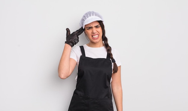 Pretty hispanic woman looking unhappy and stressed suicide gesture making gun sign market vendor concept