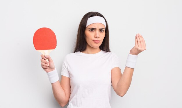 Pretty hispanic woman making capice or money gesture, telling you to pay. ping pong concept