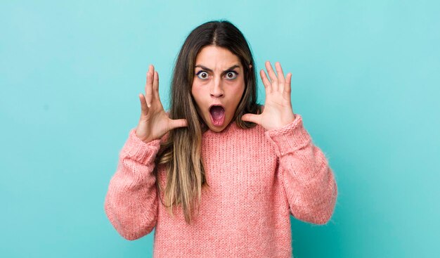 Foto bella donna ispanica che urla con le mani in aria sentendosi furiosa, frustrata, stressata e sconvolta