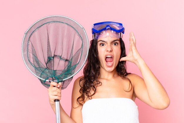 Pretty hispanic woman screaming with hands up in the air with goggles and fishing net