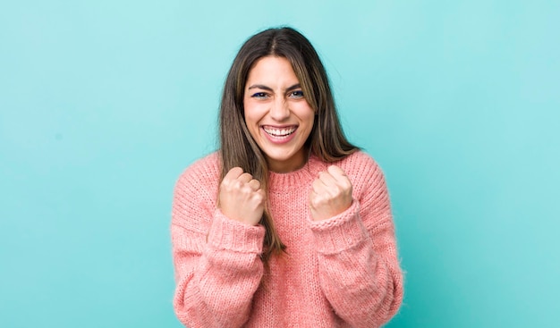 Pretty hispanic woman shouting triumphantly laughing and feeling happy and excited while celebrating success