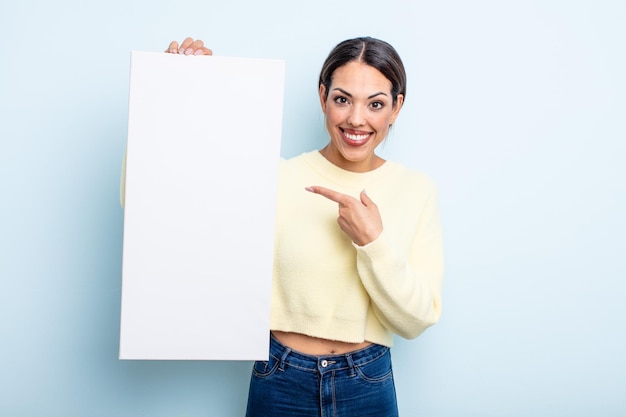 Pretty hispanic woman smiling cheerfully, feeling happy and pointing to the side. blank space concept