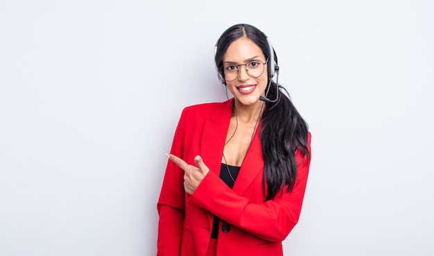 Pretty hispanic woman smiling cheerfully, feeling happy and pointing to the side. telemarketing concept