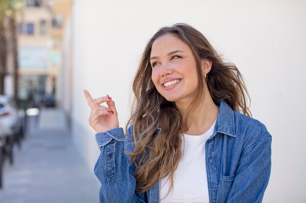 Foto bella donna ispanica che sorride felicemente e guarda di traverso chiedendosi di pensare o di avere un'idea