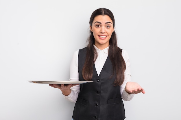 Pretty hispanic woman smiling happily with friendly and offering and showing a concept waiter with tray concept