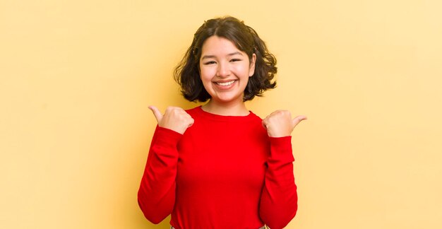 Pretty hispanic woman smiling joyfully and looking happy feeling carefree and positive with both thumbs up