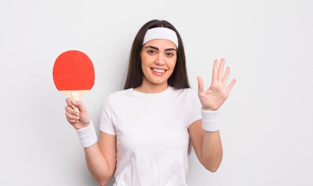 Pretty hispanic woman smiling and looking friendly showing number five ping pong concept