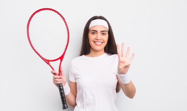 かなりヒスパニック系の女性が笑顔でフレンドリーに見え、4番目を示しています。テニスのコンセプト