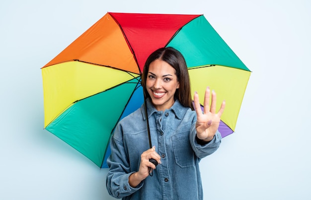 Pretty hispanic woman smiling and looking friendly, showing number four. umbrella concept