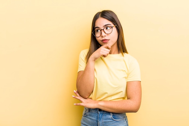 Pretty hispanic woman thinking feeling doubtful and confused with different options wondering which decision to make