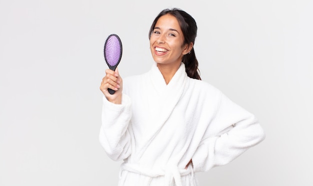 Pretty hispanic woman wearing bathrobe and holding a hair brush